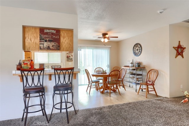 dining area featuring carpet flooring, a textured ceiling, and a ceiling fan