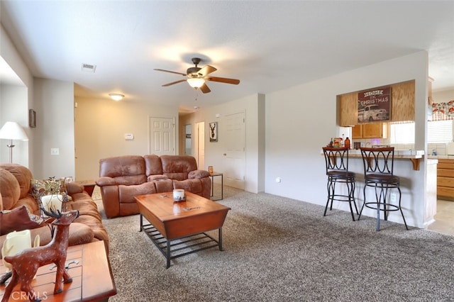 living area with light carpet, visible vents, and ceiling fan