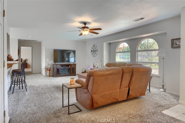 living room featuring a ceiling fan, visible vents, carpet floors, and a textured ceiling