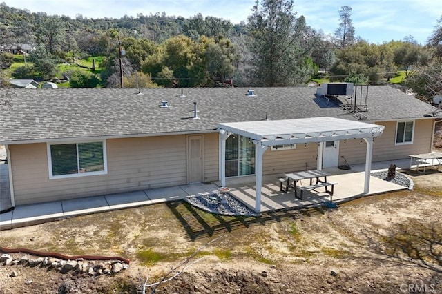 rear view of house with central air condition unit, a patio, roof with shingles, and a pergola