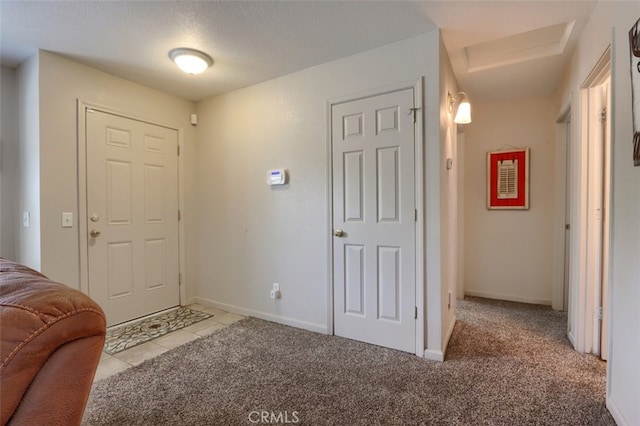 entryway with light tile patterned floors, baseboards, and light carpet