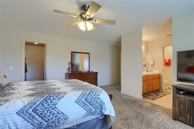 bedroom featuring a ceiling fan, visible vents, ensuite bath, a sink, and light colored carpet