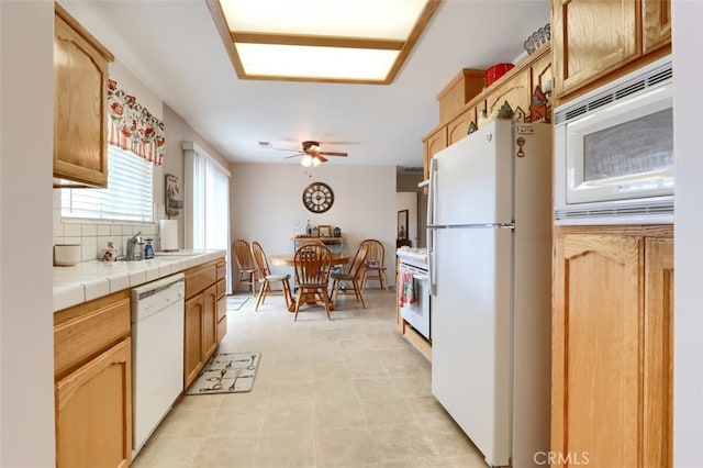 kitchen with tasteful backsplash, white appliances, a ceiling fan, and tile counters