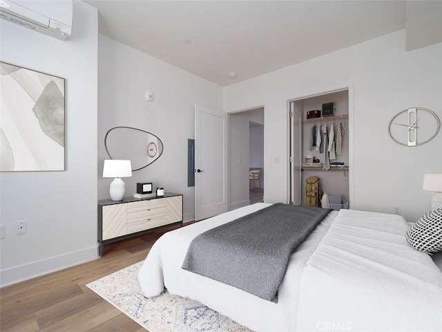 bedroom featuring baseboards, wood finished floors, and a wall unit AC