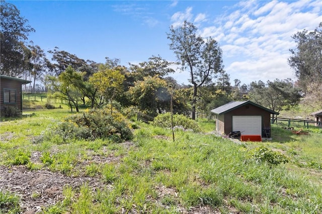 view of yard with an outbuilding, driveway, a garage, and fence