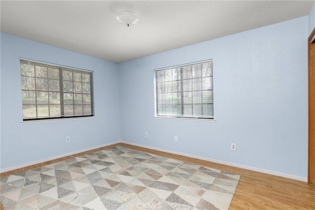 spare room featuring baseboards and light wood finished floors