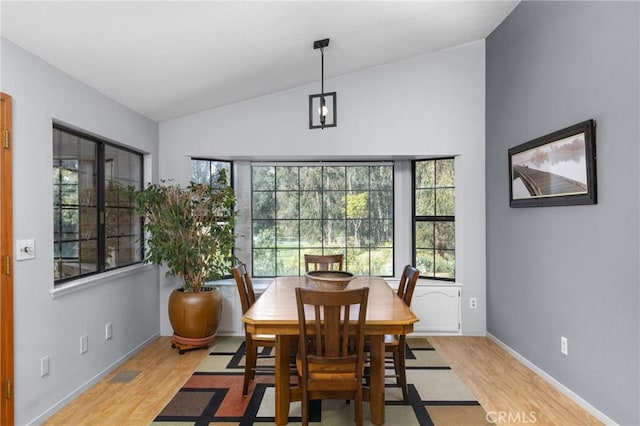 dining area featuring baseboards, lofted ceiling, and light wood-style floors