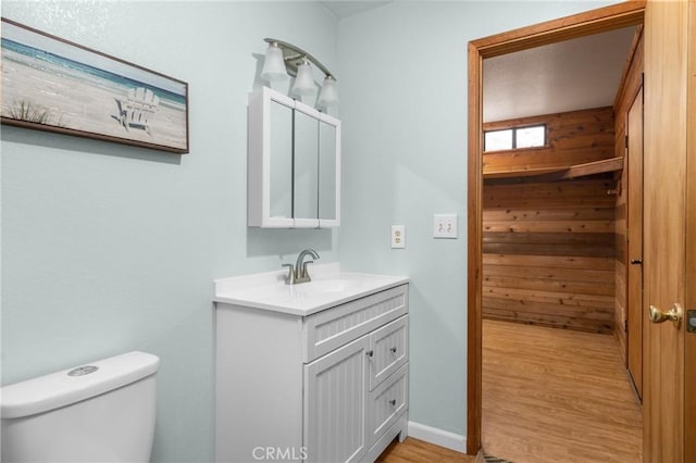 bathroom featuring baseboards, toilet, wood finished floors, and vanity