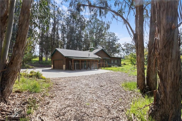 rear view of property with an attached garage and driveway