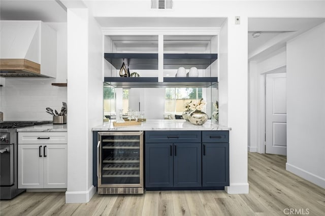 3242 Harmona Pl, Los Alamitos, CA 90720 - bar with decorative backsplash, stainless steel range, light wood-style flooring, and beverage cooler