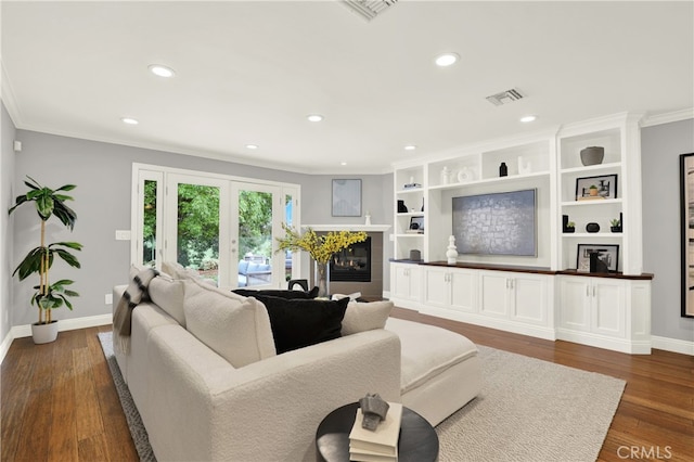 living room featuring visible vents, dark wood-style floors, ornamental molding, and a tile fireplace