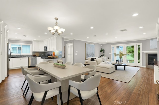 dining space featuring dark wood finished floors, recessed lighting, a fireplace, and ornamental molding