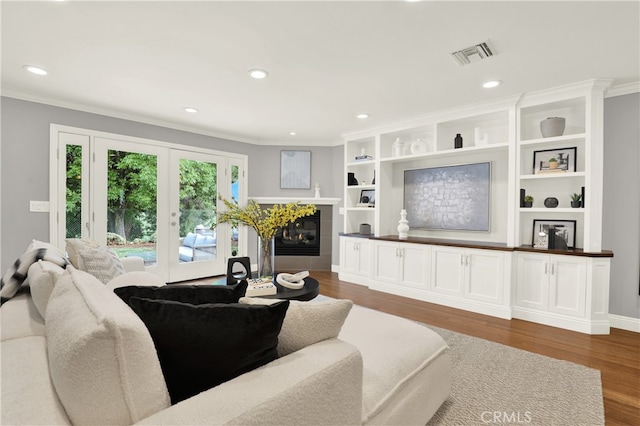 living room with visible vents, a fireplace, crown molding, and wood finished floors