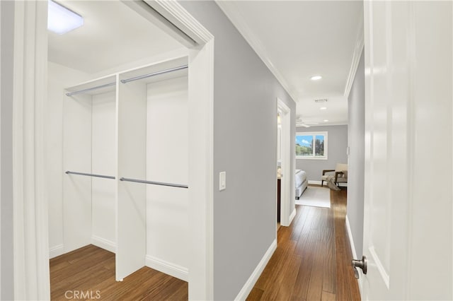 hall featuring hardwood / wood-style flooring, recessed lighting, baseboards, and ornamental molding