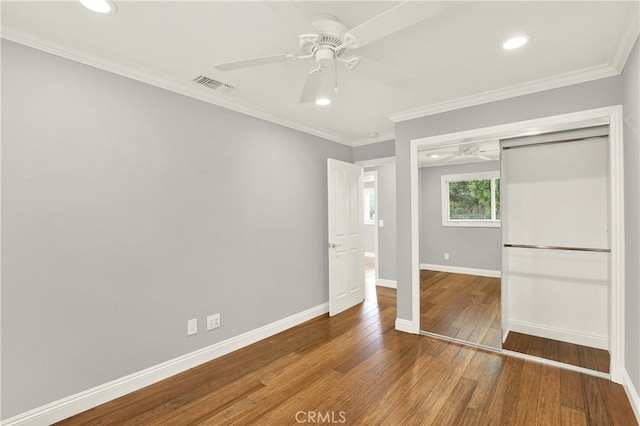 unfurnished bedroom featuring visible vents, crown molding, baseboards, hardwood / wood-style floors, and a closet