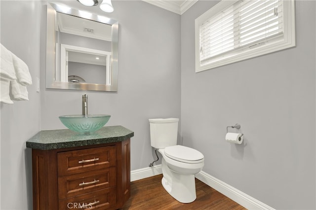 half bath featuring baseboards, toilet, ornamental molding, wood finished floors, and vanity