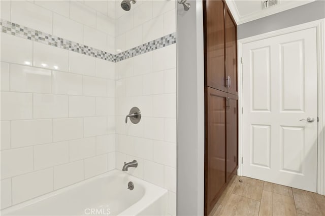 full bathroom featuring wood finish floors, visible vents, shower / bathtub combination, and crown molding