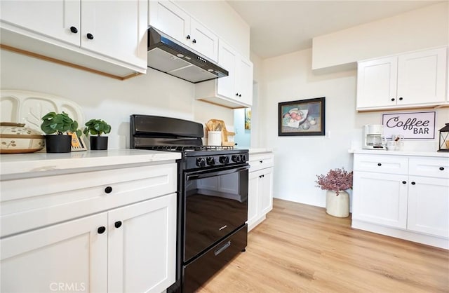 kitchen with under cabinet range hood, black gas range oven, white cabinets, and light countertops