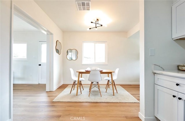 dining space with visible vents, baseboards, and light wood finished floors