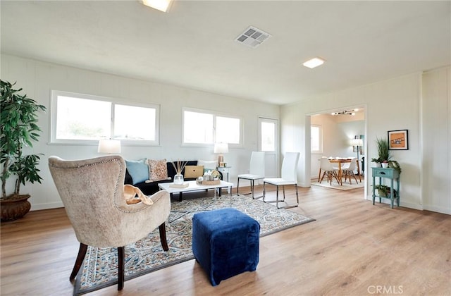 living room with visible vents, plenty of natural light, baseboards, and wood finished floors