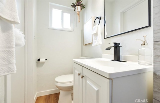 bathroom featuring baseboards, toilet, wood finished floors, and vanity