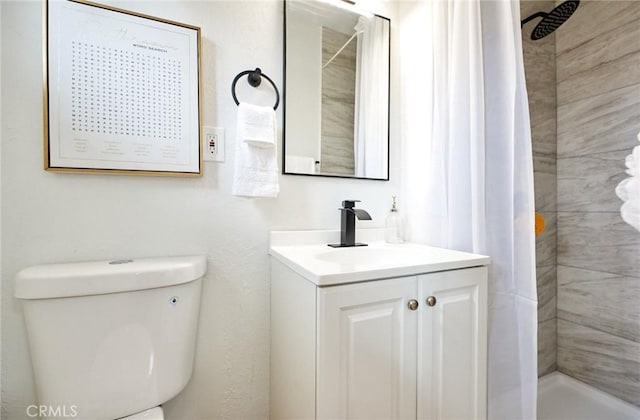 bathroom with toilet, vanity, and a tile shower