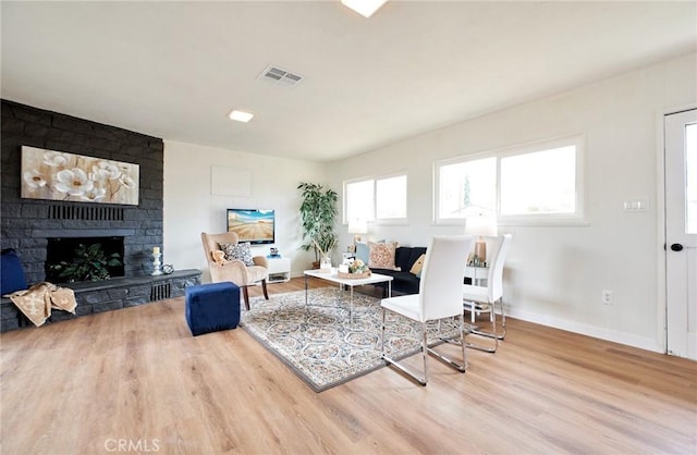 living area with visible vents, a large fireplace, baseboards, and wood finished floors