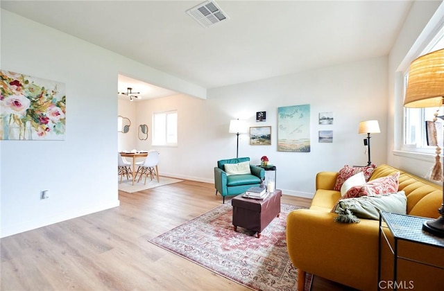 living area featuring visible vents, baseboards, and wood finished floors