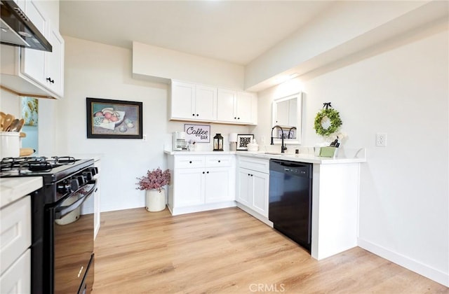 kitchen featuring black appliances, light countertops, light wood-style floors, under cabinet range hood, and white cabinetry