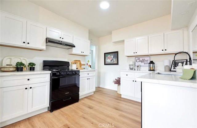 kitchen with white cabinetry, gas stove, light wood-type flooring, and under cabinet range hood