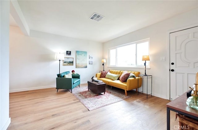 living room featuring visible vents, light wood-style flooring, and baseboards