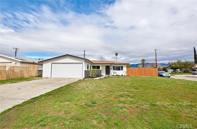 view of front of home with a front yard, fence, driveway, stucco siding, and a garage