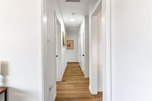 hallway with light wood-type flooring and baseboards