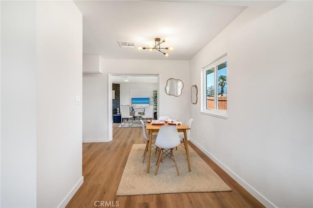 dining room with wood finished floors, baseboards, and a chandelier