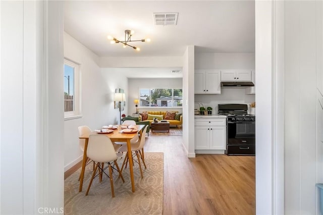 dining area featuring light wood finished floors, a chandelier, and baseboards