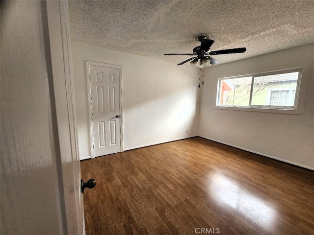 empty room featuring a textured ceiling, ceiling fan, and wood finished floors