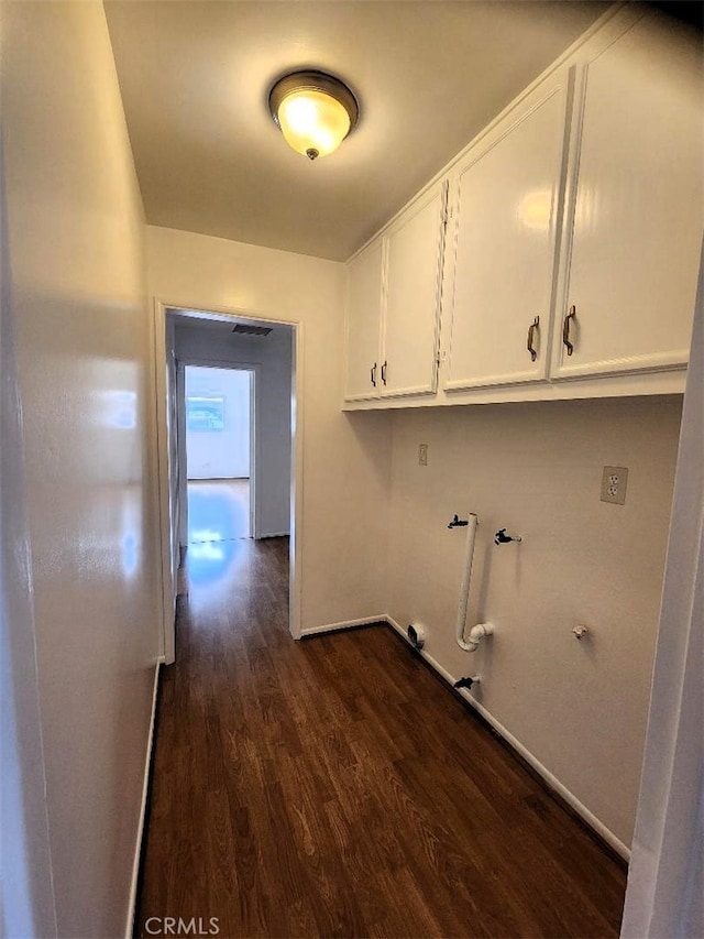 laundry room featuring dark wood finished floors, hookup for a gas dryer, cabinet space, baseboards, and hookup for a washing machine