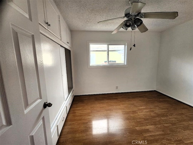 unfurnished bedroom with a closet, a textured ceiling, ceiling fan, and dark wood-style flooring