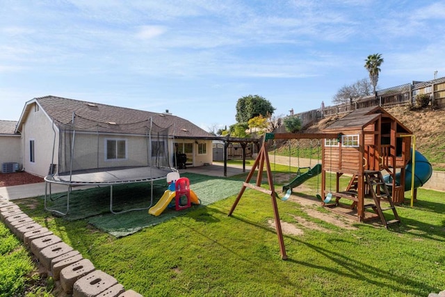 view of play area with a trampoline, fence, central AC, a lawn, and a patio