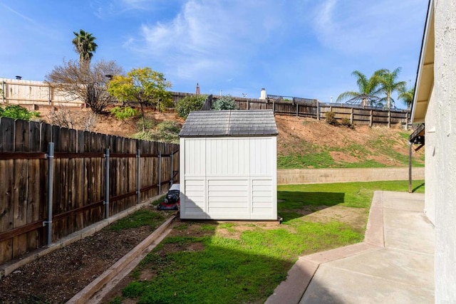 view of yard featuring an outbuilding, a storage shed, a patio, and a fenced backyard