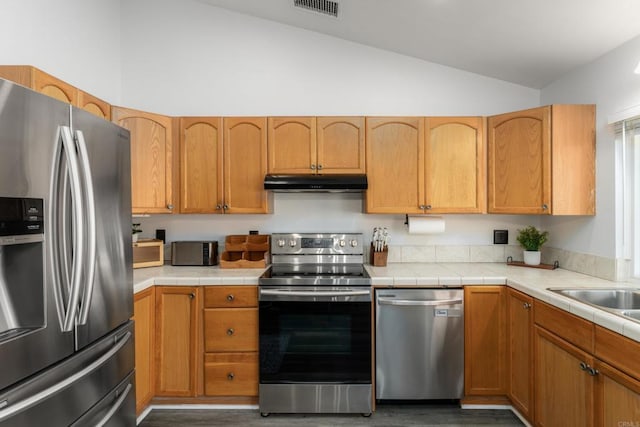 kitchen featuring visible vents, under cabinet range hood, lofted ceiling, appliances with stainless steel finishes, and wood finished floors