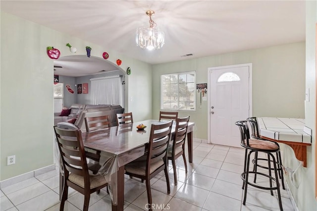 dining area featuring light tile patterned floors, visible vents, arched walkways, and baseboards