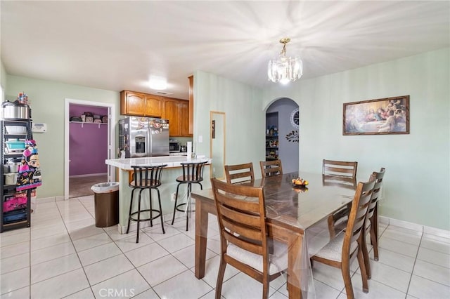 dining area with arched walkways, light tile patterned floors, an inviting chandelier, and baseboards