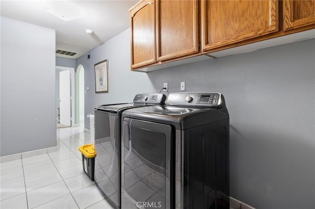 laundry room with visible vents, washer and dryer, cabinet space, arched walkways, and light tile patterned floors