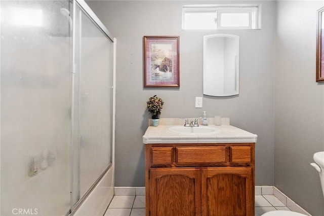 bathroom with tile patterned flooring, baseboards, toilet, enclosed tub / shower combo, and vanity