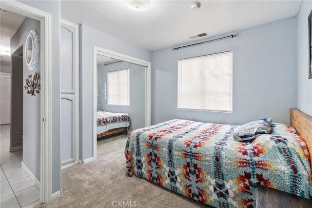 carpeted bedroom with baseboards, visible vents, and a closet