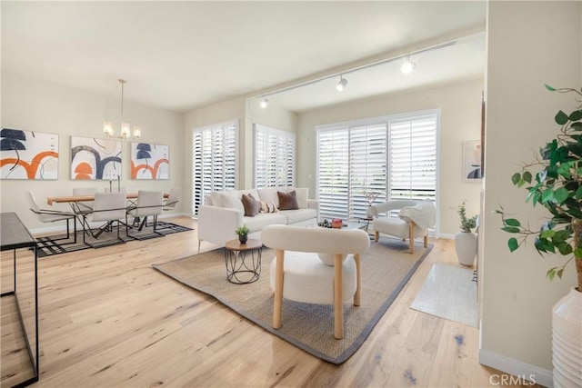 living room featuring baseboards, a notable chandelier, wood finished floors, and track lighting