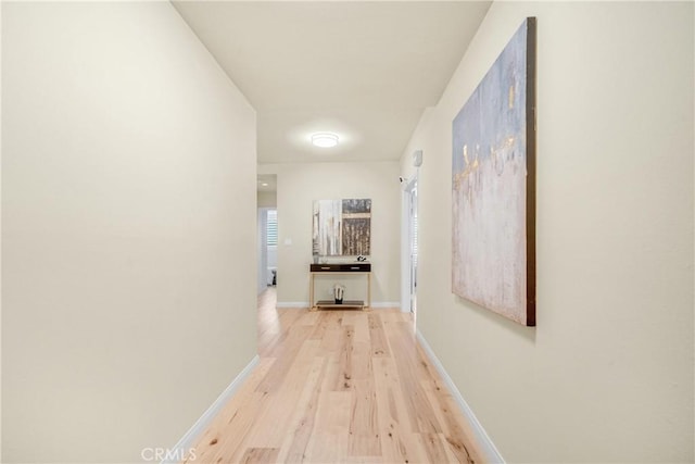 corridor featuring baseboards and light wood-style flooring