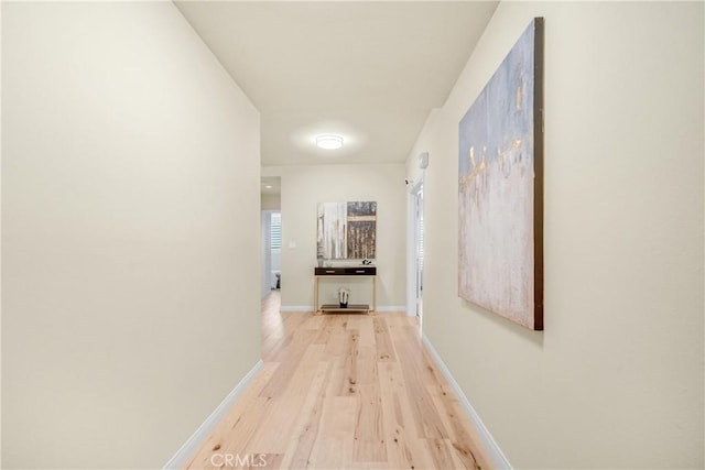hall featuring light wood-style floors and baseboards