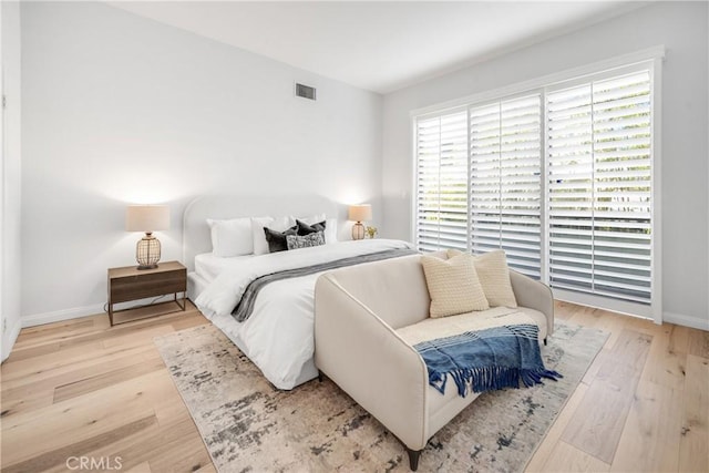 bedroom featuring wood finished floors, visible vents, and baseboards